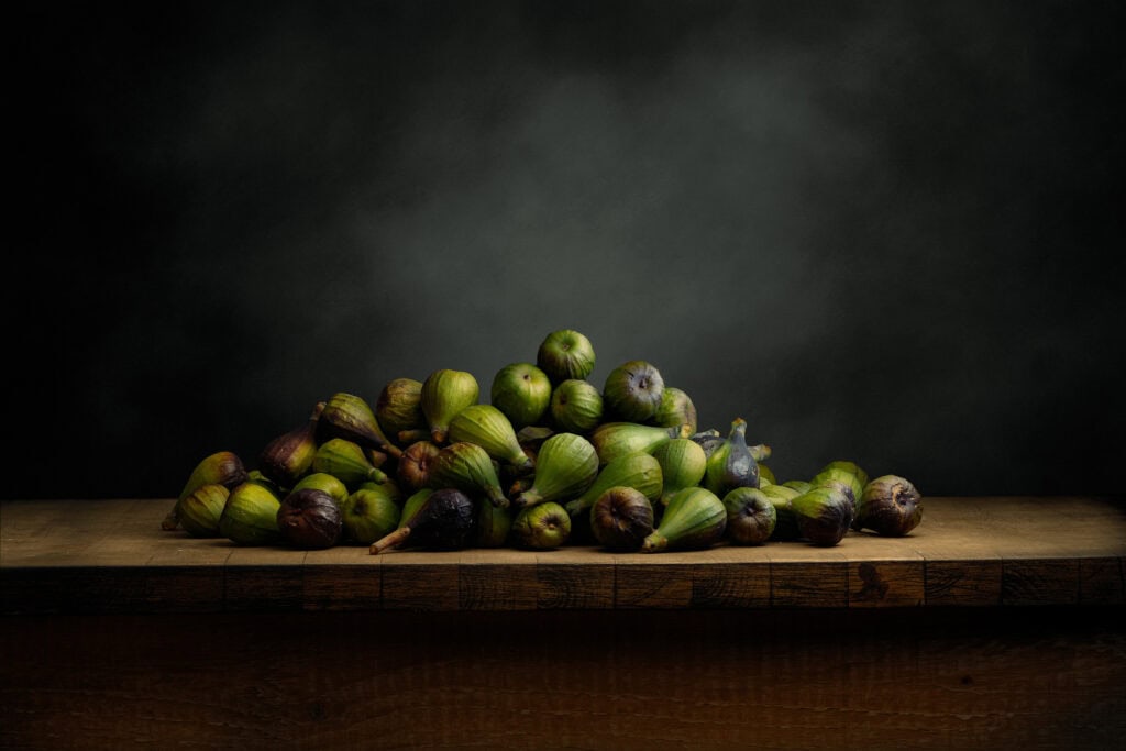Bodegón artístico de higos verdes y negros sobre tabla de madera. Fotografía de Jaime Mugaburu