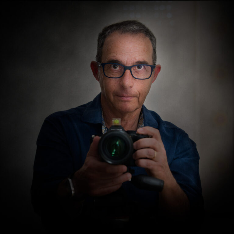 Autorretrato del fotógrafo Jaime Mugaburu sosteniendo su cámara en el estudio, especializado en fotografía artística de bodegón.